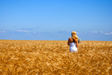 Naklejka na ściany i meble Ukraine. Beautiful landscape of a wheat field with a girl in white.