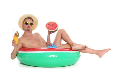 Shirtless man with inflatable ring, watermelon and glass of cocktail on white background