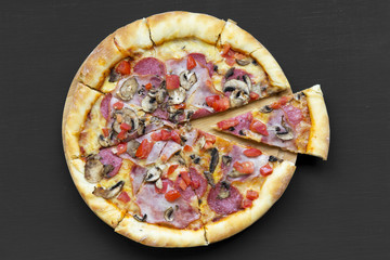 Freshly baked pizza on black background. Flat lay, overhead, top view. Closeup.