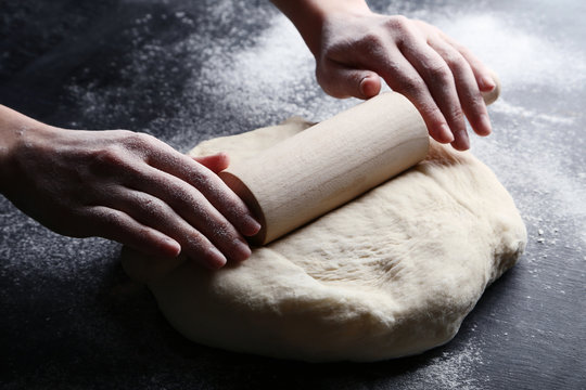 Female hands rolling dough on wooden table
