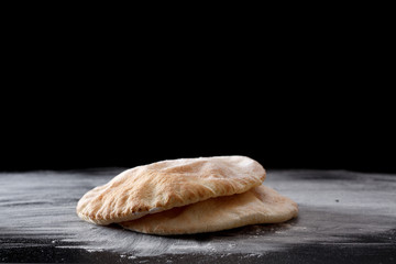 Pita bread on a black table sprinkled with flour