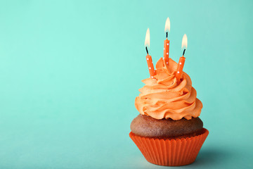 Tasty cupcake with candles on a mint background