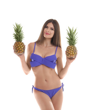Sexy young woman in bikini with pineapples on white background