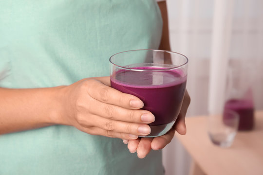 Woman holding glass of delicious acai juice, closeup