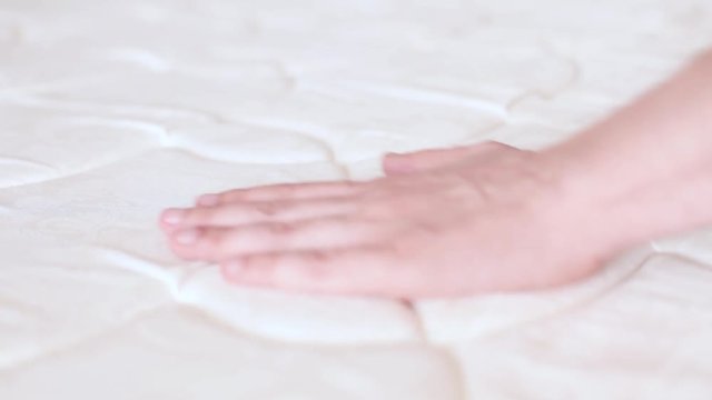 man touch the mattress on the bed