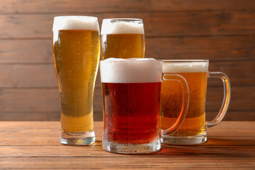 Glasses with different types of cold tasty beer on wooden table