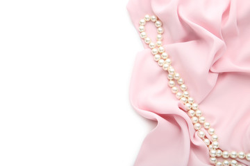 Pearl necklace with pink satin fabric on white background