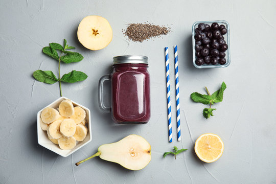 Flat lay composition with ingredients for delicious acai cocktail and juice in mason jar on gray table