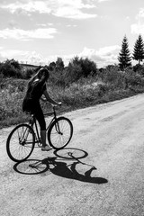 girl riding a bicycle on a road on a sunny summer day,  vacation in countryside, black and white