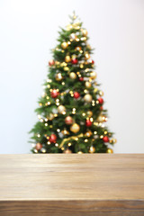 Wooden table and blurred Christmas tree with fairy lights on background