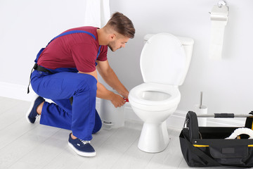 Young man working with toilet bowl in bathroom