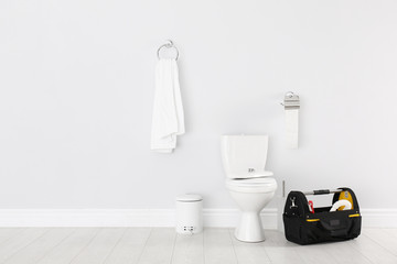Plumbing tool kit bag near toilet bowl in bathroom
