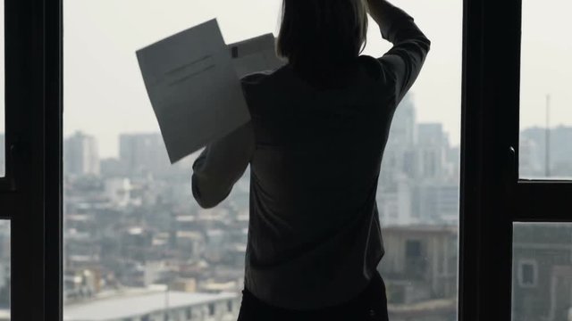 Overwhelmed businesswoman throwing documents in office
