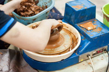A kid teached by adult master at the pottery master-class
