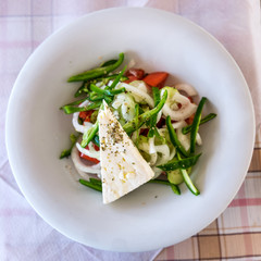 Greek salad with sheep Feta Cheese on white plate on a table in a Mediterranean Restaurant