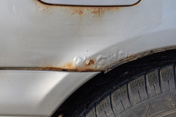 Rust over the wheel of a silver car