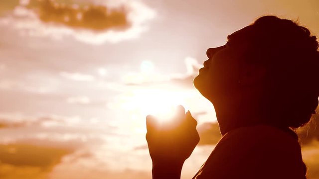 the girl prays. lifestyle Girl folded her hands in prayer silhouette at sunset. slow motion video. Girl folded her hands in prayer pray to God. girl praying asks forgiveness for sins of repentance