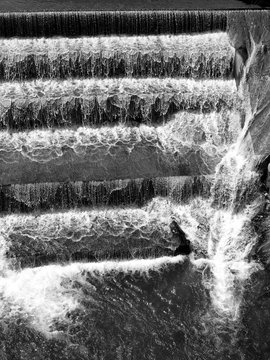 Staustufen am Stauwehr mit herabst&uuml;rzenden Wassermassen mit wei&szlig;er Gischt am Lechfall im Sommer bei Sonnenschein in F&uuml;ssen am Lech im Ostallg&auml;u im Freistaat Bayern in neorealistischem Schwarzwei&szlig;