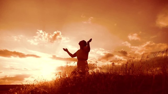 Girl folded her hands in prayer silhouette lifestyle at sunset. woman praying on her knees. slow motion video. Girl folded her hands in prayer pray to God. the girl praying asks forgiveness for sins