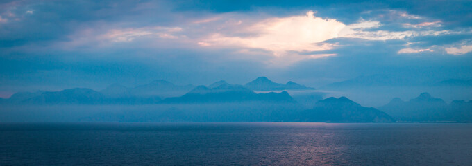 panorama view to the mountines and sea at blue hour, with beautiful rays of light  throw the clouds