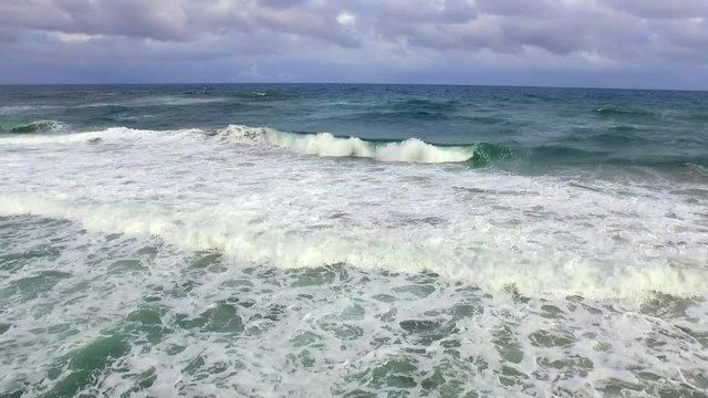 Drone footage of waves gliding over the oceans surface near the coast.