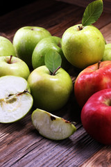 Ripe red apples with leaves on wooden background.