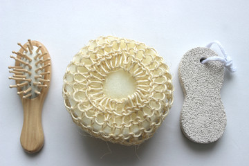 Hygiene products. Set of accessories for the bath. Wooden comb, loofah sponge and pumice on white background