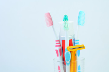 Toothbrushes in glass and Razor on white background with copy space