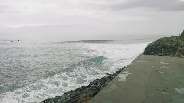 Surfers surf on waves of atlantic ocean on shore of Madeira