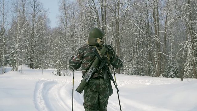 Group of soldiers run on skis in the woods with weapons. Clip. Soldiers with AK-47 rifles and grenade launchers running through the winter forest on skis. Soldiers on exercises in the woods in winter