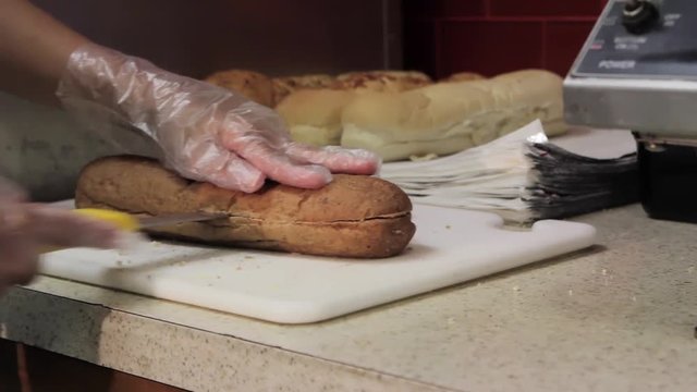 Chef slicing bread in the kitchen.