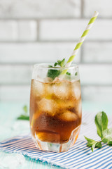 The glass of peach ice tea on wooden table. Cuba Libre or long island iced tea cocktail, cold drink or lemonade with fruits and mint