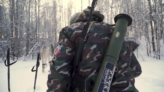 Group of soldiers run on skis in the woods with weapons. Clip. Soldiers with AK-47 rifles and grenade launchers running through the winter forest on skis. Soldiers on exercises in the woods in winter