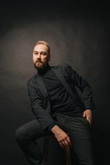 Elegant handsome man in classical suit poses in studio theatre.