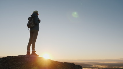Crane shot: A woman traveler stands on top of a mountain, looks at the beautiful landscape ahead,...