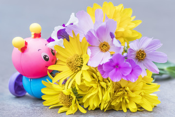 Toy caterpillar next to a bouquet of wildflowers, close-up