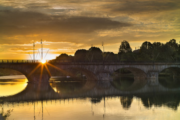 sun rises through old bridge in the morning in Turin in Italy