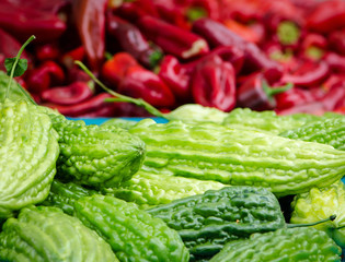 Bitter melons and red peppers at a farmer's market stall.