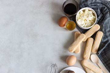 Ingredients for making traditional Italian dessert Tiramisu: mascarpone cheese, savoiardi, cocoa, coffee, brandy and eggs on light grey background. Copy space
