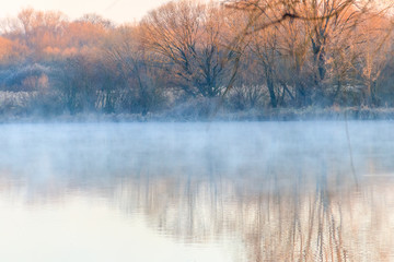 Peaceful lake in the mist. Fog over pond at morning