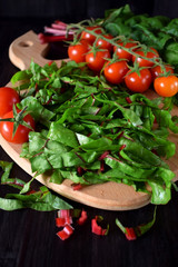 Chopped chard leaves on a cutting board and cherry tomatoes next to it