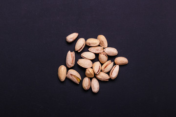 Handful of pistachios on a black background - healthy snack. Top view. Copy space.