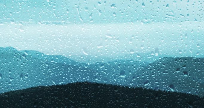 Mountain landscape view through rainy glass window.