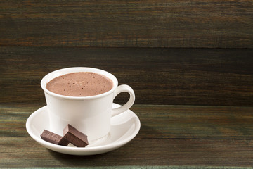 Hot chocolate and pieces of chocolate on wooden background
