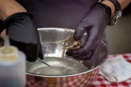 Shucking Fresh Oysters, Man's Hands In Black Gloves With Knife And On A Seafood Market. Gastronomic Gourmet Dainty Products On Market Counter, Real Scene, Food Market