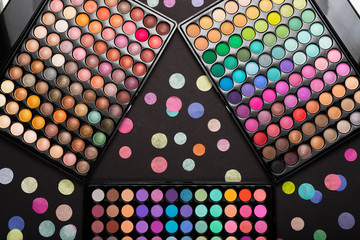 Colorful make-up palettes and colorful confetti on black background