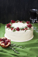 Chocolate cake with berry cream, white cheese cream, pomegranate berries and rosemary branches. Two glasses of red wine. Idea for a birthday cake or for a wedding cake.