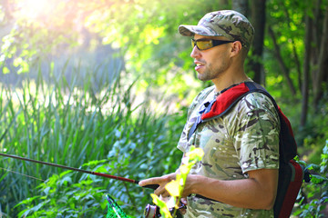 Fisherman with a fishing rod in a hand near the river bulrush.