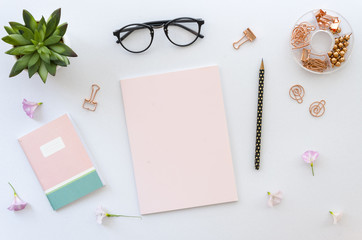 Flat lay, top view office table desk workspace with office accessories including blank paper for lettering, notepad, glasses and plant on white background. mockup