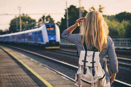 woman is looking at arriving train at a railway station